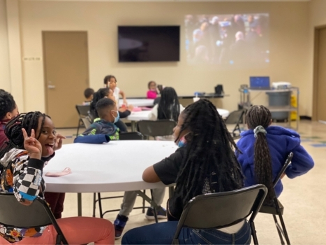 young adults sit together at round tables at the palw
