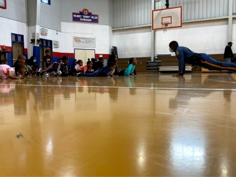 a police officer shows a group of children how to do a pushup