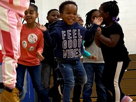 a young boy smiles in front of a group of other young children